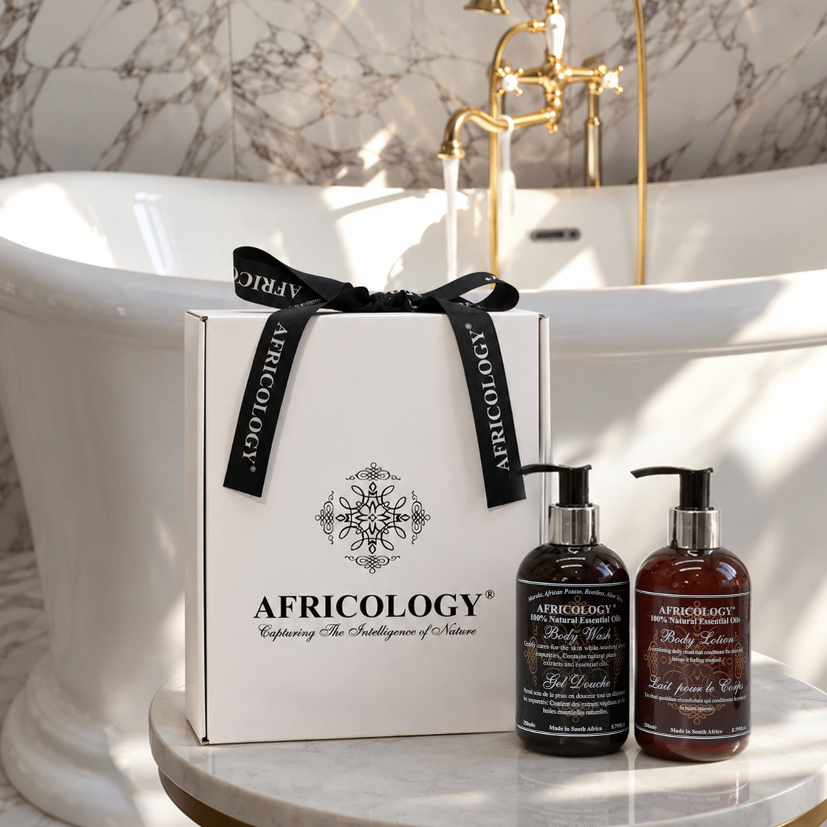 Africology gift box and two 250ml pump bottles styled beside a freestanding bath