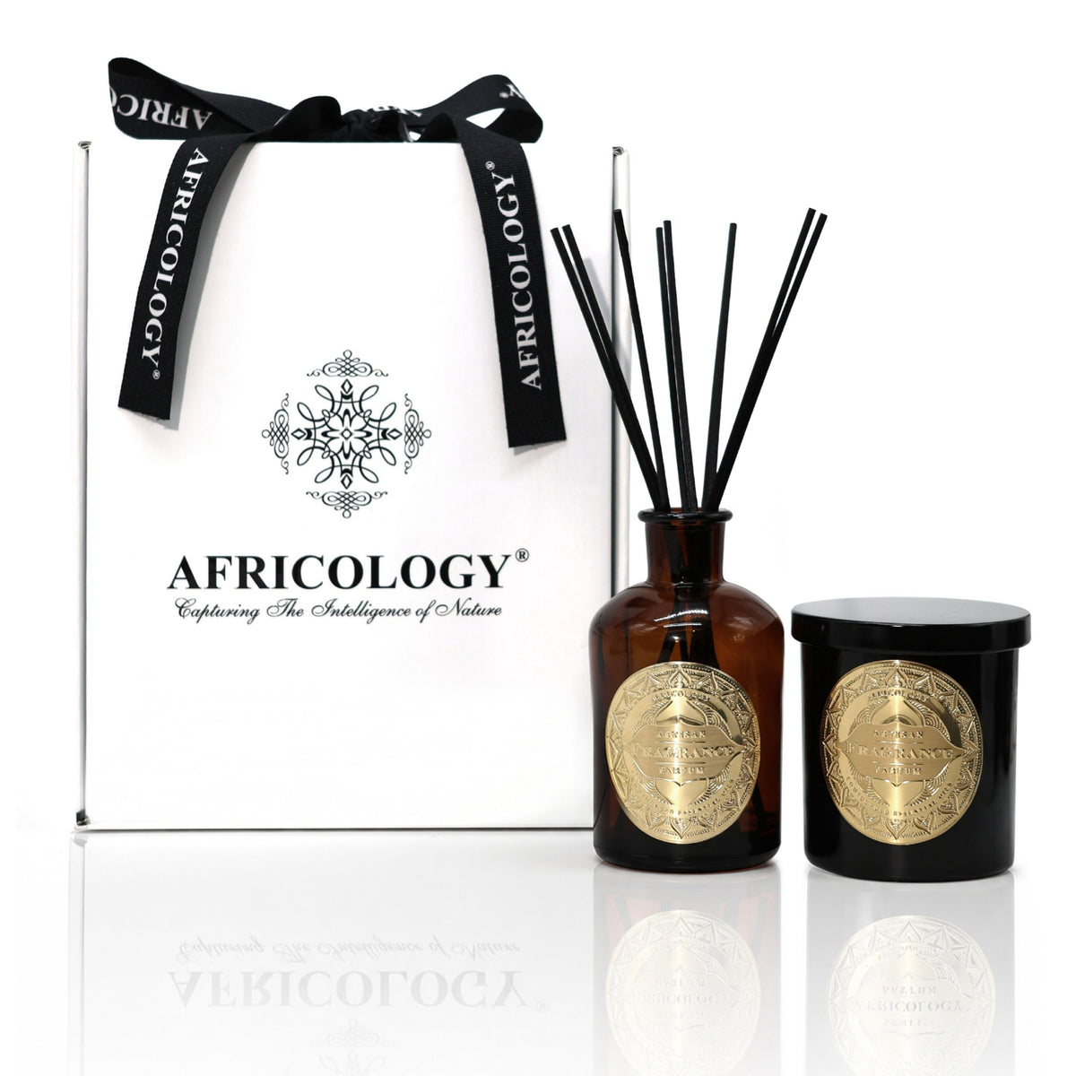 Africology reed diffuser and scented candle beside the bespoke white and black Africology gift box with ribbon