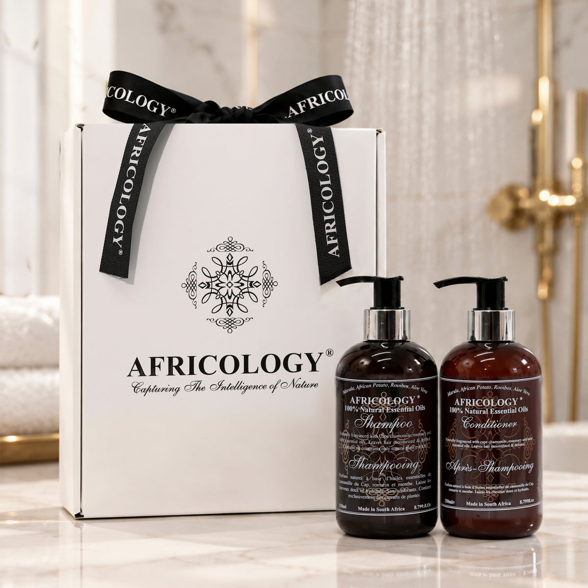 Africology Shampoo and Conditioner gift box styled on marble beside a rainfall shower